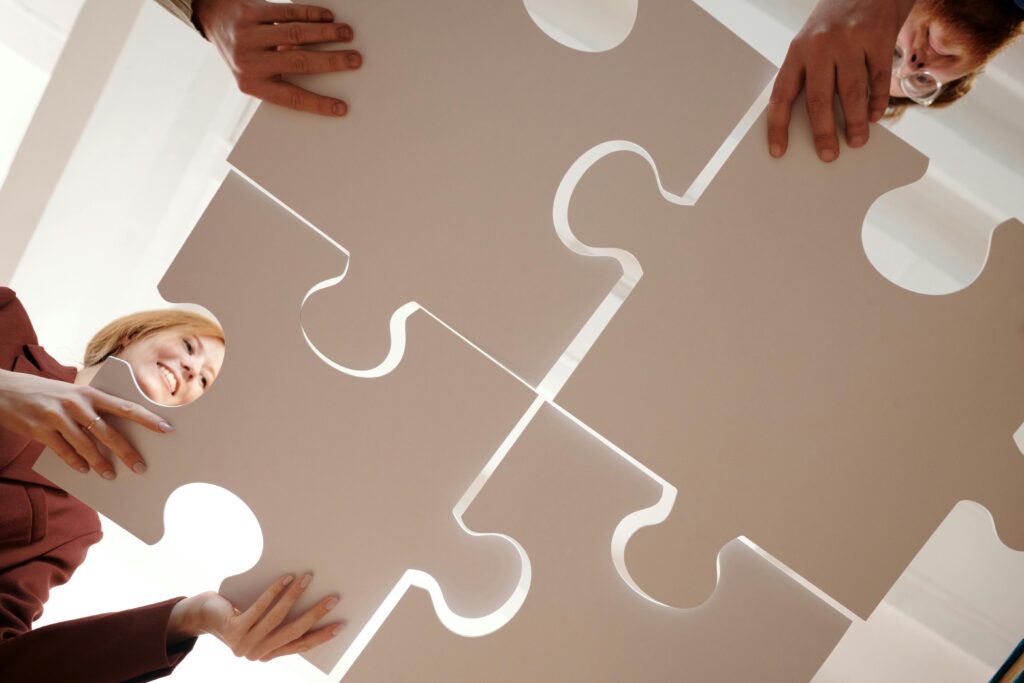 Low angle view of diverse team assembling large puzzle pieces, symbolizing unity and cooperation.